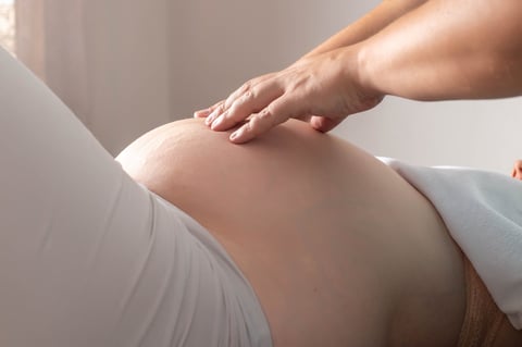 An osteopathic doctor palpates the belly of a pregnant girl in the third trimester. Preparation before childbirth. Osteopathy and pregnancy, physiotherapy
