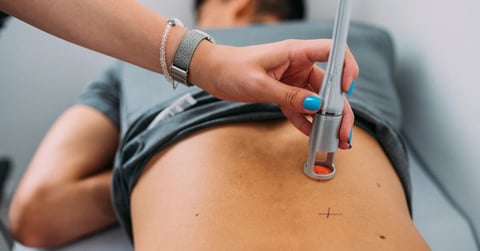 Medical professional performing ultrasound examination on patients abdomen using handheld probe