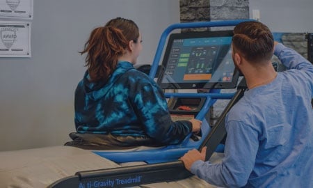 Two people examining a blue diagnostic machine with a screen in an indoor setting