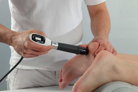 Medical professional using an ultrasound or scanning device on a patients ankle during a diagnostic examination