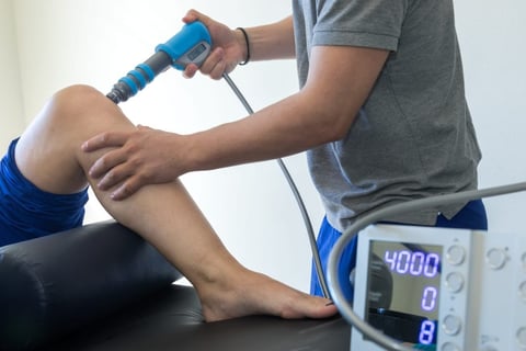 Therapist using ultrasound therapy device on patients knee during rehabilitation treatment